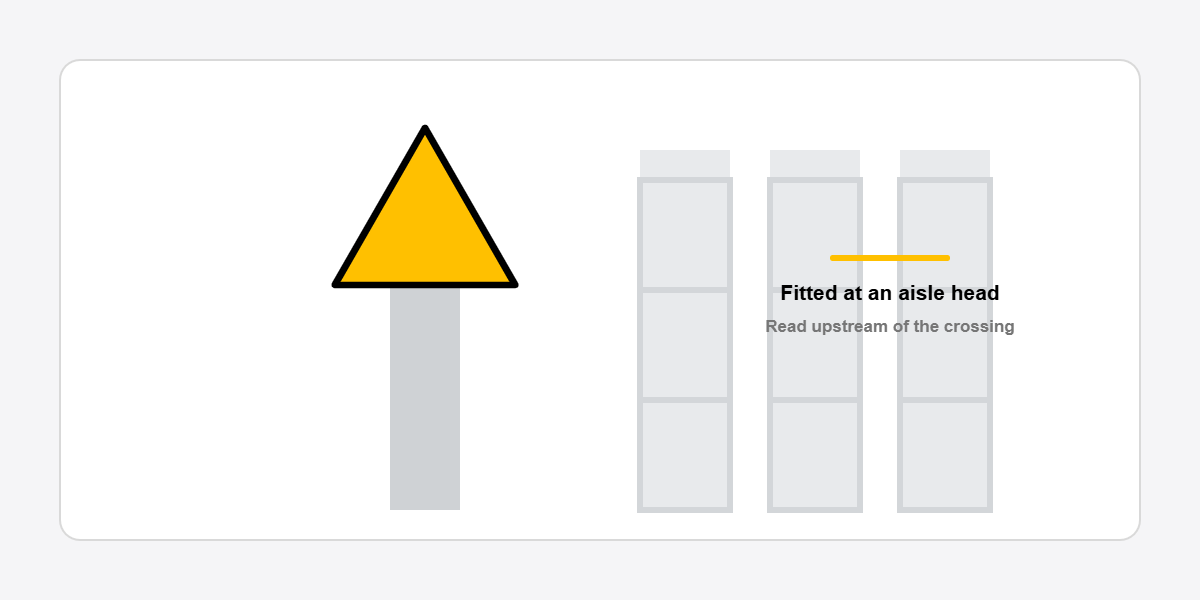 yellow triangular warning sign fitted to a concrete post in a warehouse aisle